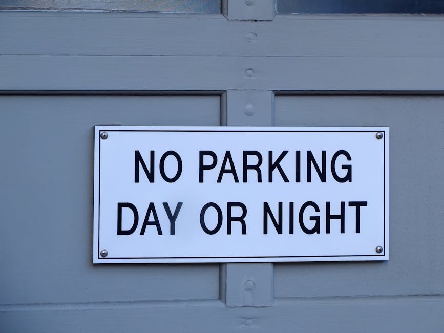 A green and white parking restriction sign mounted on a metal pole outdoors, indicating a two-hour parking limit from 8 am to 8 pm, except on Sundays. The sign features the words '2 HOUR PARKING' prom